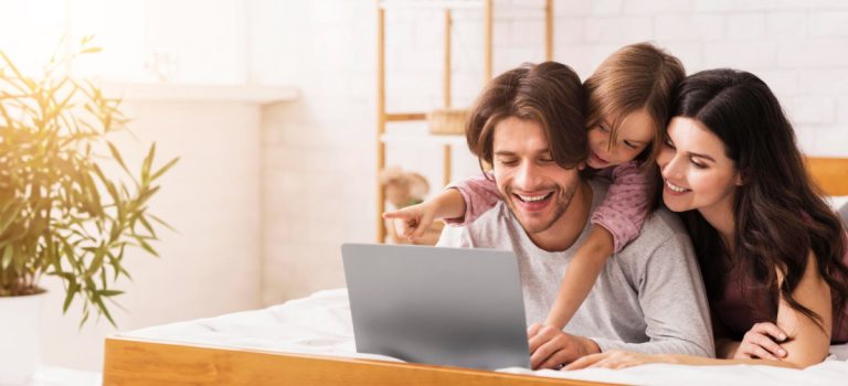 A smiling family looking at a laptop together at home