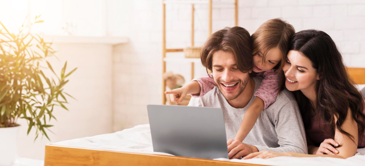 A smiling family looking at a laptop together at home