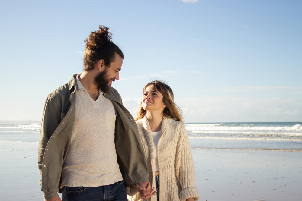 A smiling couple holding hands on the beach