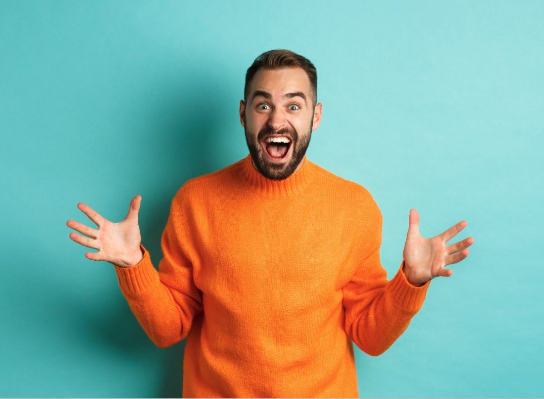 An excited man in an orange jumper celebrating